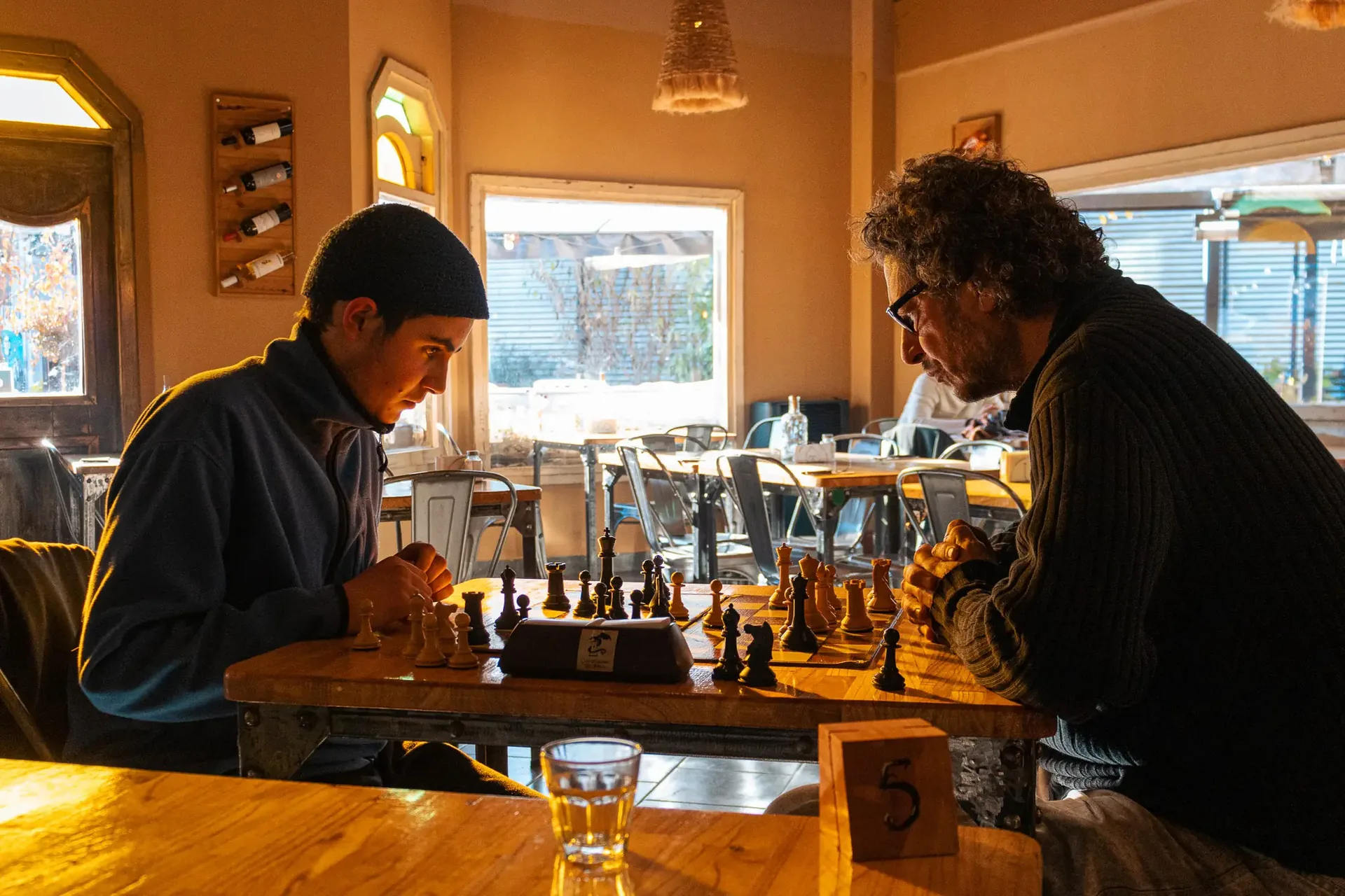 Dos personas conversando en la barra de una cervecería con luz cálida — cobertura de evento