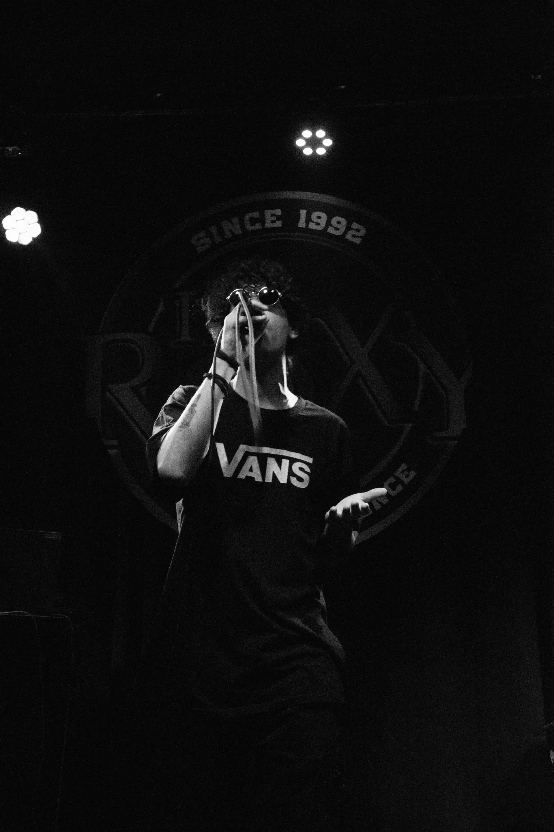 Cantante de rap en vivo frente al logo del local, blanco y negro