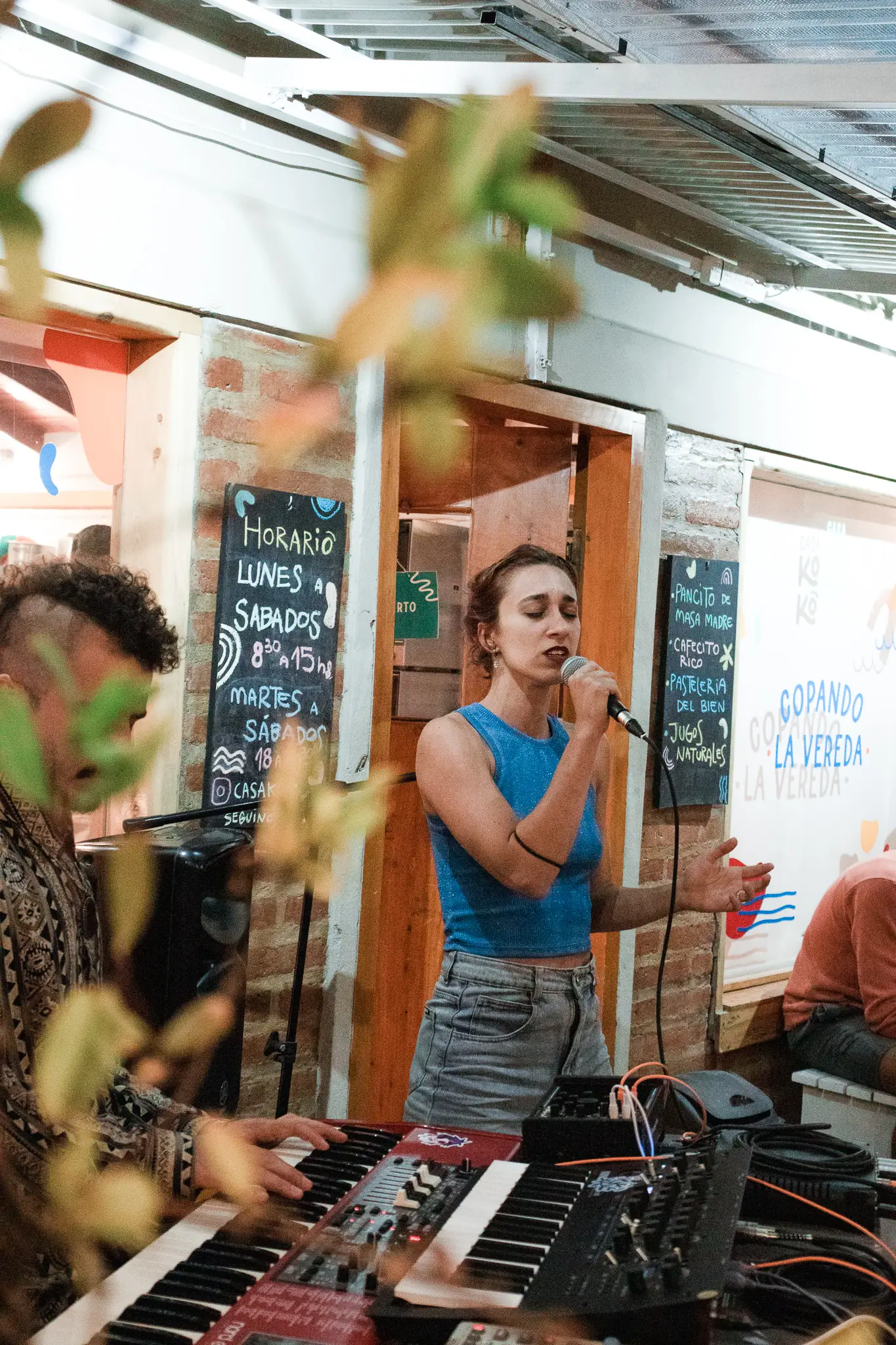 Cantante tocando el teclado en vivo en un patio, entre plantas — show íntimo