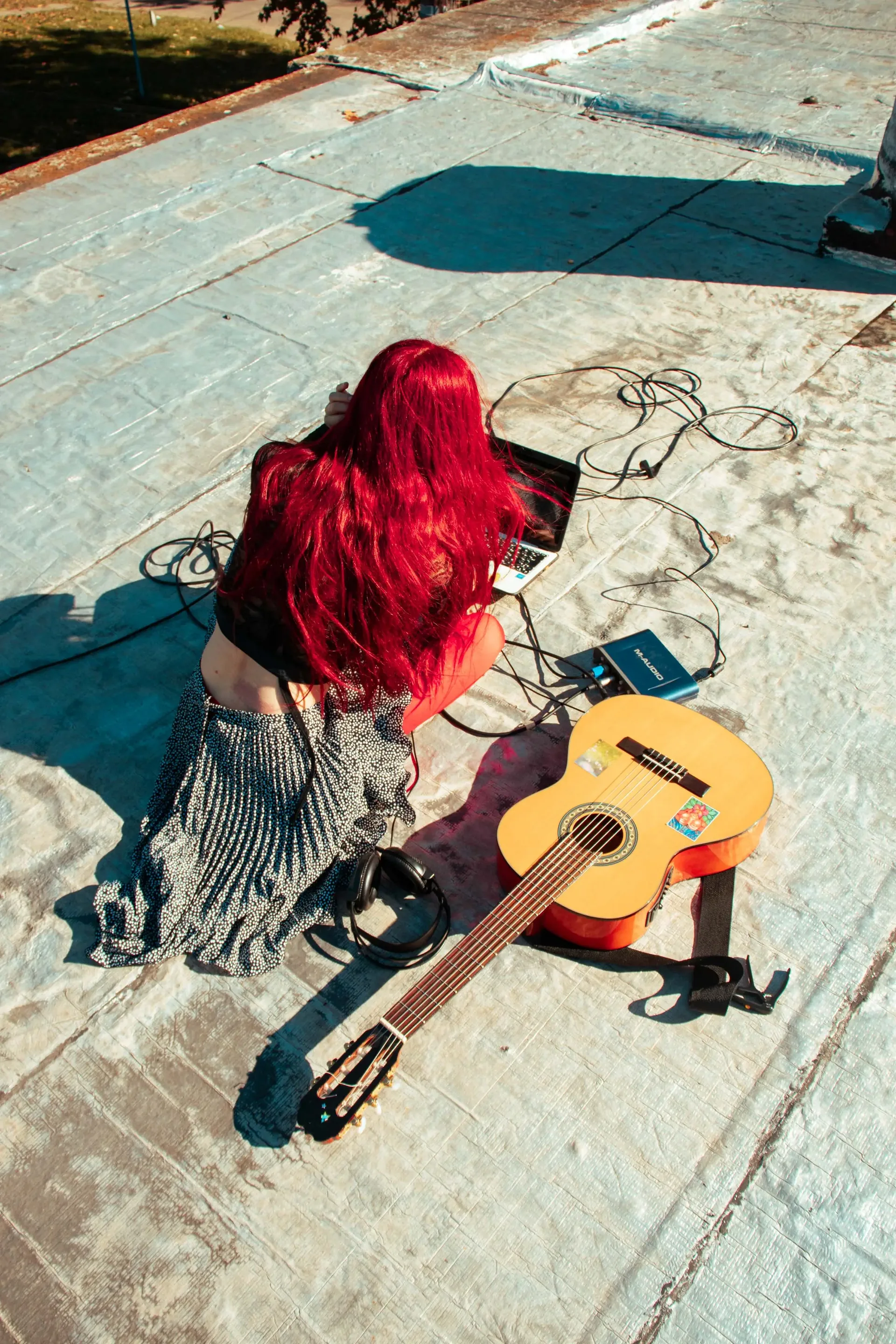 Toma cenital de una persona sentada en el piso junto a su guitarra criolla