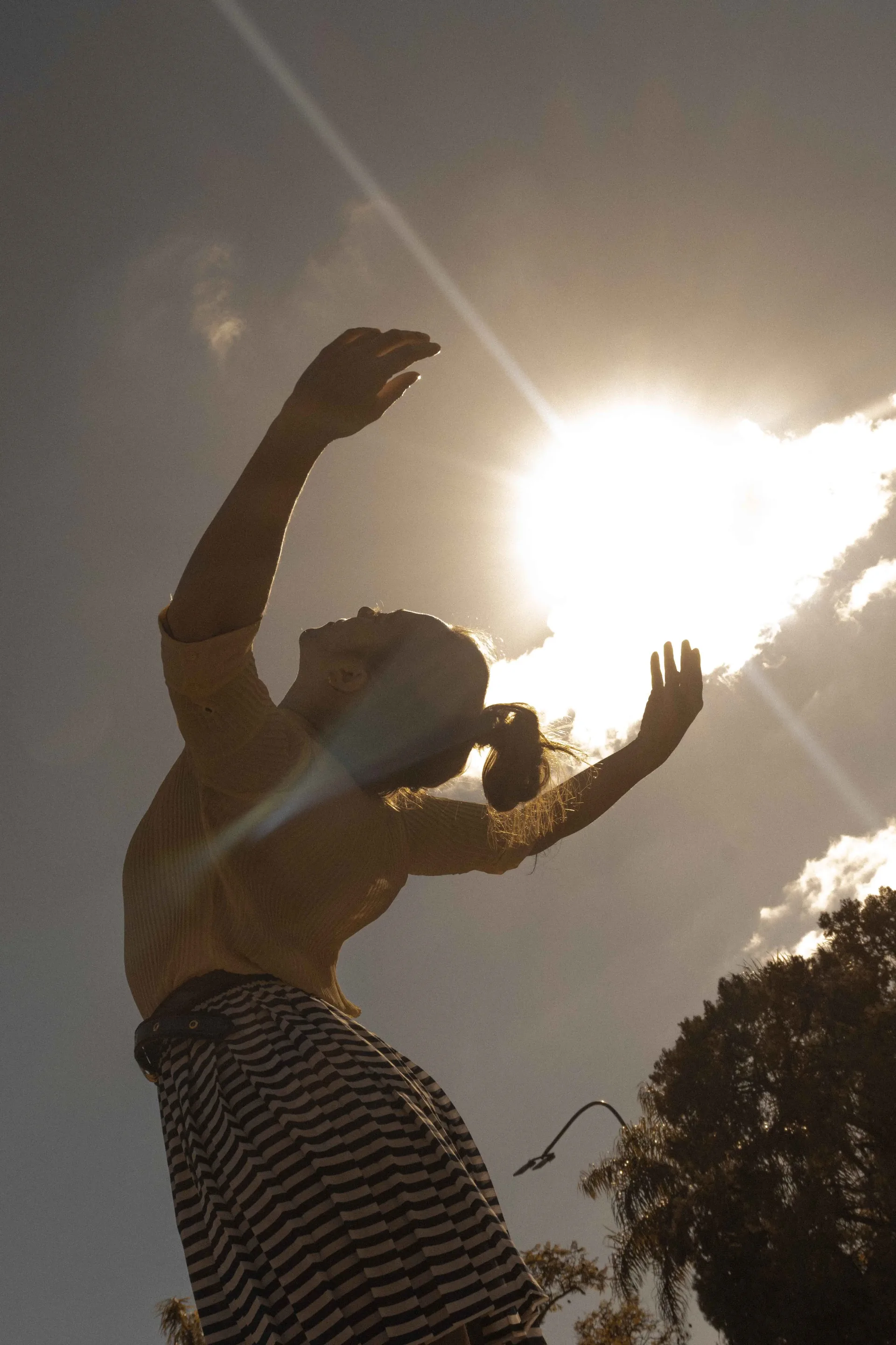 Retrato a contraluz con los brazos en alto frente al sol