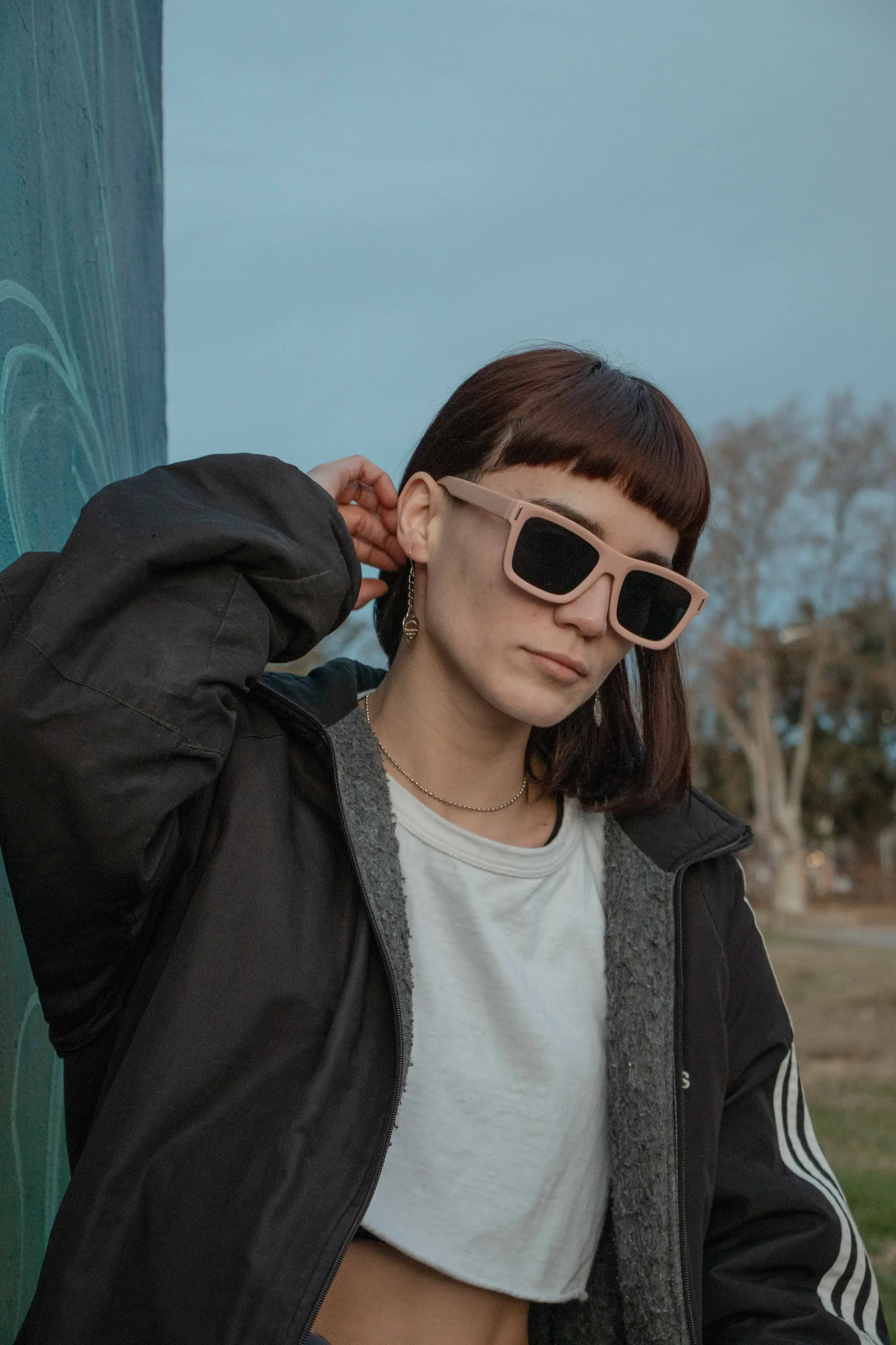 Retrato al aire libre con anteojos de sol y campera bajo el cielo despejado